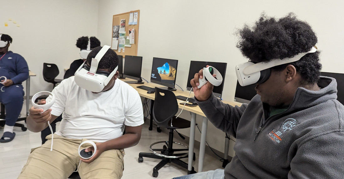 2 students in chairs using vr headsets to draw 3d models